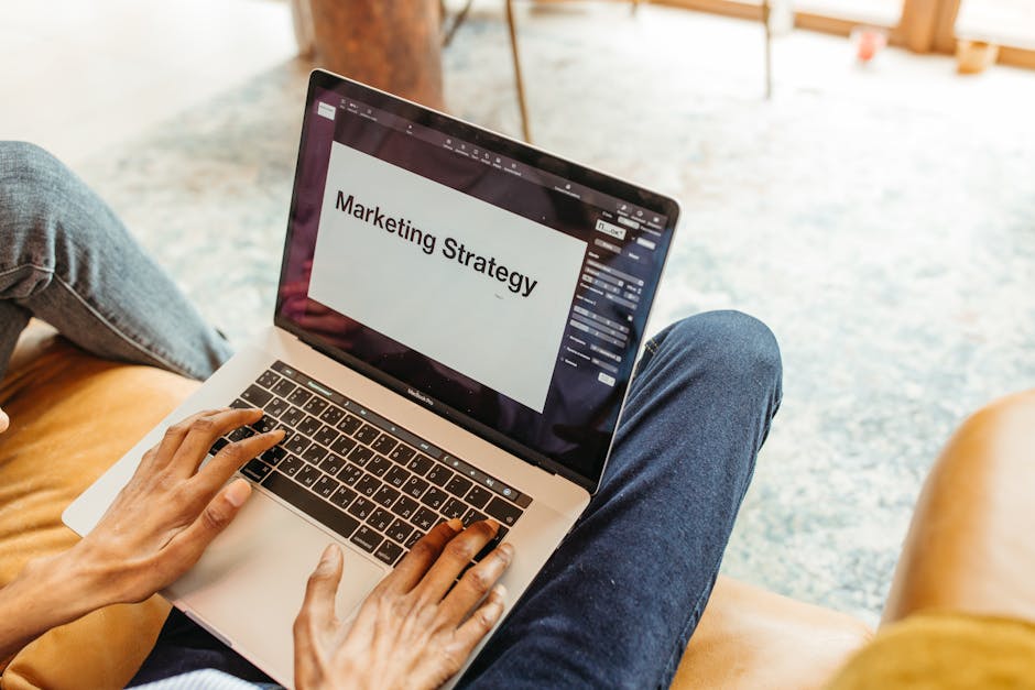 Close-up of hands using a laptop displaying a marketing strategy presentation indoors