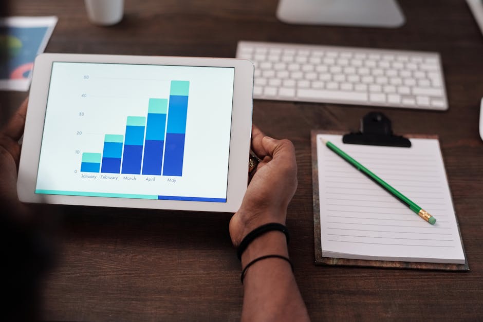 Close-up of a person holding a tablet showing growth charts on a wooden desk setup