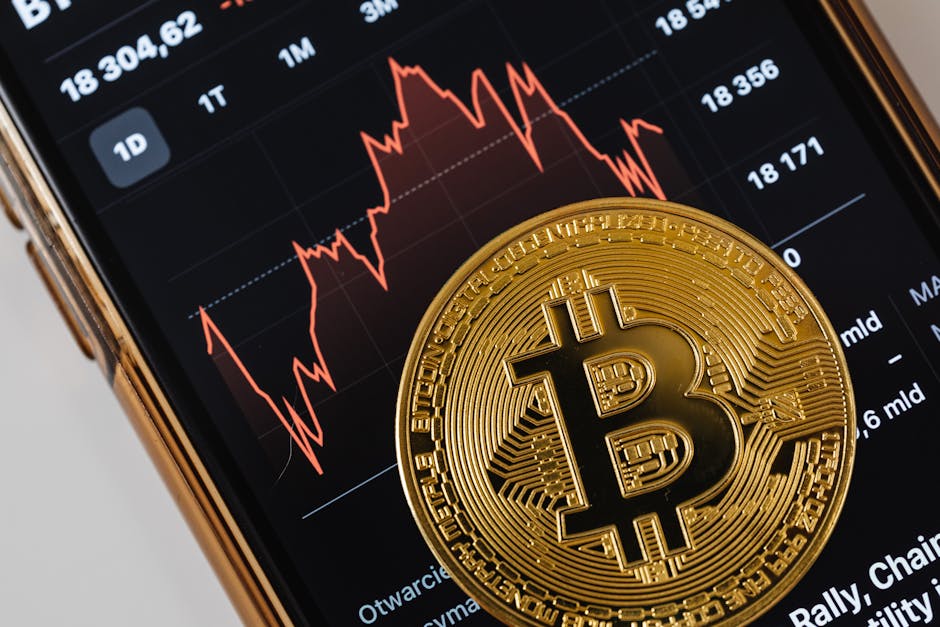 A close-up of a gold Bitcoin coin placed on a smartphone displaying a stock market chart